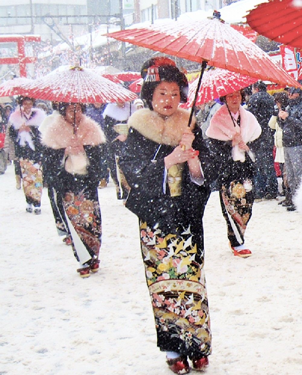 雪の中赤い傘で練り歩く丸髷（まるまげ）行列