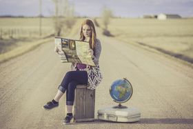 スーツケースに座り地図を見る女性
